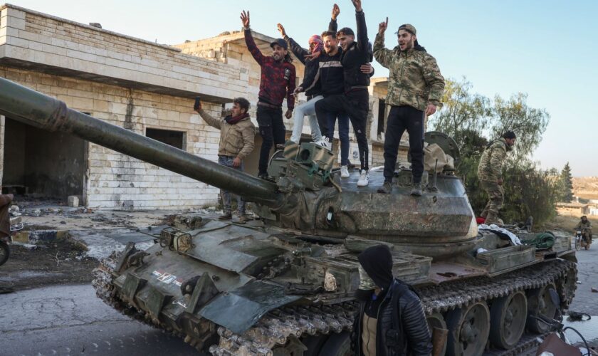 Opposition supporters stand on a captured Syrian army tank near Aleppo. Pic: AP Photo/Omar Albam