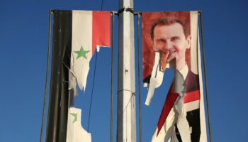 Un drapeau national syrien et un portrait du président syrien Bachar al-Assad dséchirés par des combattants antigouvernementaux dans la ville d'Alep, dans le nord de la Syrie, le 30 novembre 2024