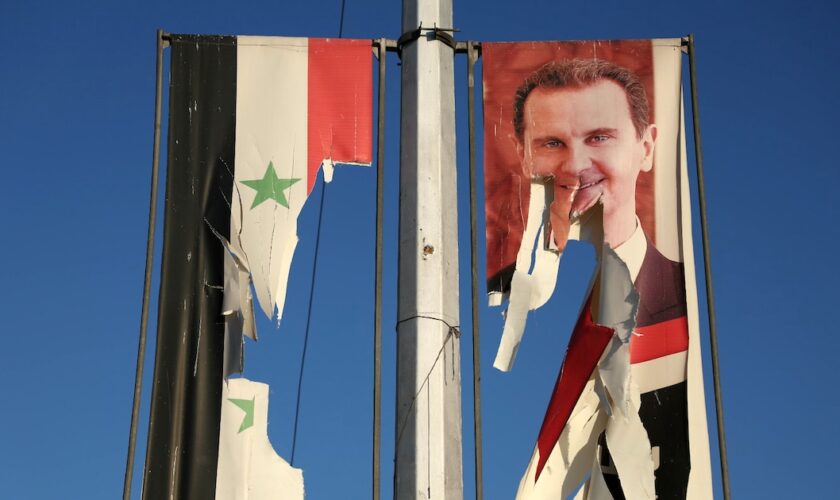 Un drapeau national syrien et un portrait du président syrien Bachar al-Assad dséchirés par des combattants antigouvernementaux dans la ville d'Alep, dans le nord de la Syrie, le 30 novembre 2024