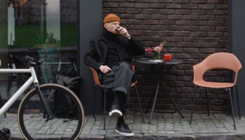 Ein Mann im Winter, der vor einem Caffe sitzt und seinen Kaffe trinkt