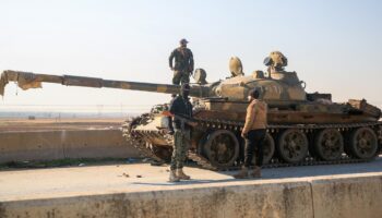 Des combattants rebelles près d'un char abandonné par l'armée syrienne à al-Safirah, au sud-est d'Alep, dans le nord de la Syrie, le 3 décembre 2024