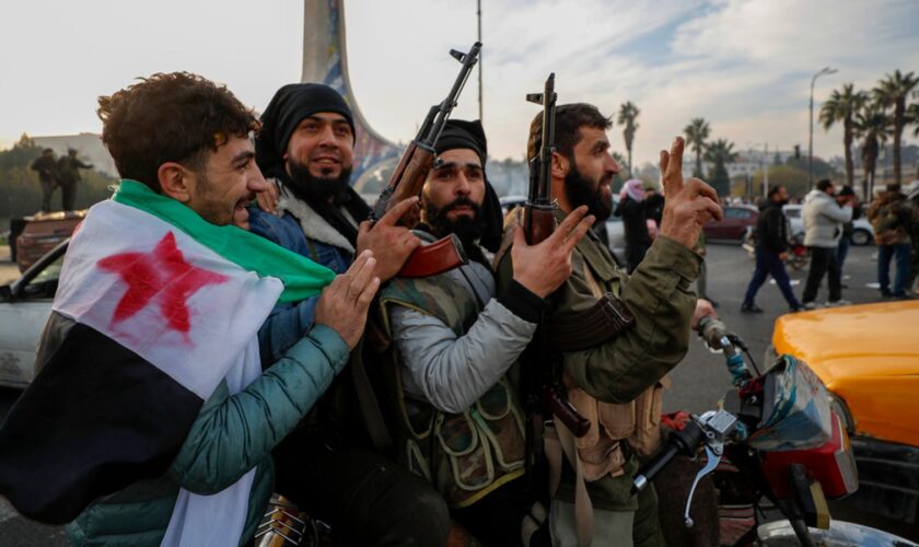 Syrian opposition fighters celebrate after the Syrian government collapsed in Damascus, Syria, Sunday, Dec. 8, 2024. (AP Photo/Omar Sanadiki)