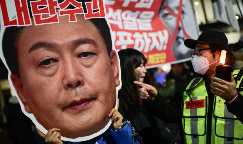 Un manifestant brandit un portrait du président sud-coréen Yoon Suk Yeol, lors d'un rassemblement pour sa démission, le 8 décembre 2024 à Séoul