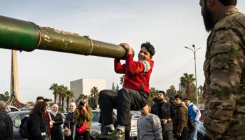 Ein Jugendlicher hält sich in Damaskus aus lauter Freude über den Umsturz in Syrien an einem Panzerrohr fest