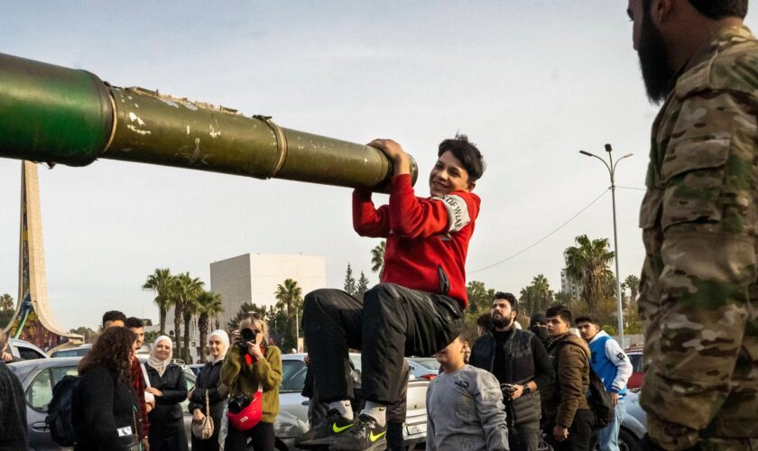 Ein Jugendlicher hält sich in Damaskus aus lauter Freude über den Umsturz in Syrien an einem Panzerrohr fest