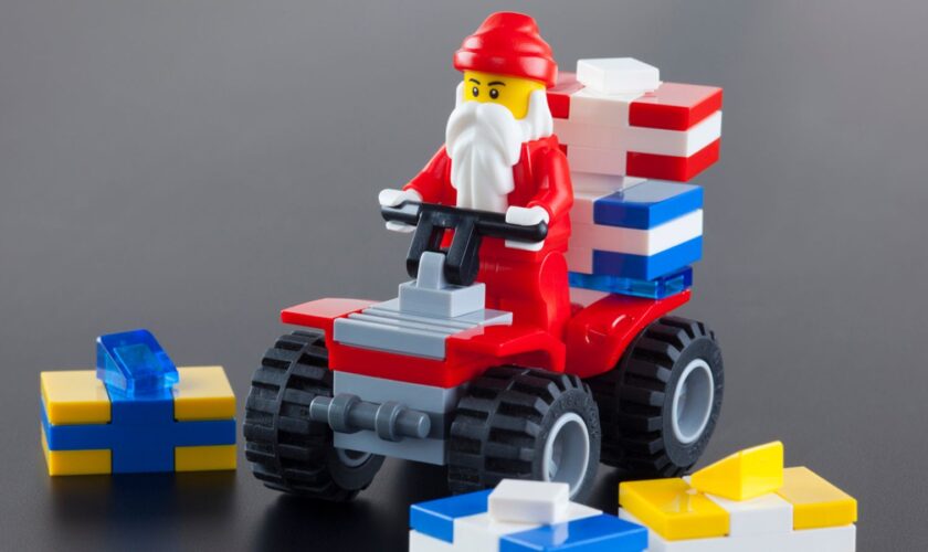 Tambov, Russian Federation - October 04, 2013 Lego Santa Claus minifigure on red quadrocycle with gift boxs on black background. Studio shot. LEGO is a popular line of construction toys manufactured by the Lego Group (Billund, Denmark).