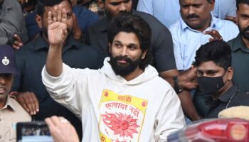 Indian Southern film actor Allu Arjun, center, greets his fans in Hyderabad, India, Friday, Dec. 13, 2024, as he leaves a hospital where he was taken for medical checkup by policemen before arresting him after his appearance at a film screening allegedly led to a crush of fans in which a woman died. (AP Photo)