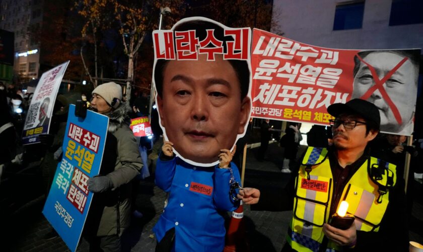 A participant wearing a mask of South Korean President Yoon Suk Yeol attends a rally demanding his impeachment outside the National Assembly in Seoul, South Korea, Sunday, Dec. 8, 2024.The signs read "Arrest Yoon Suk Yeol." (AP Photo/Ahn Young-joon)