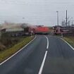 Death-defying moment truck driver stuck at railway level crossing leaps from vehicle just as a freight train smashes into it