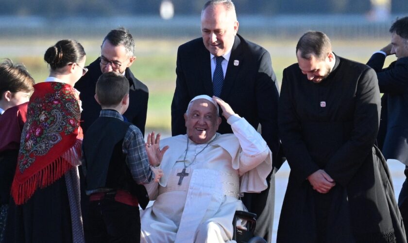 Le pape François est accueilli par le ministre de l'Intérieur Bruno Retailleau (g) et des enfants à son arrivée l'aéroport d'Ajaccio, le 15 décembre 2024