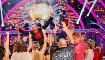 Chris McCausland celebrates his win, as Dianne Buswell holds the glitterball trophy aloft. Pic: PA