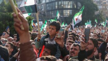 Des Syriens brandissent le drapeau de l'époque de l'indépendance adopté par les nouvelles autorités en Syrie, lors des célébrations dans la ville de Homs, dans le centre de la Syrie, le 13 décembre 2024