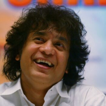 FILE - Indian Tabla expert Zakir Hussain laughs during a press conference to announce a musical concert in Mumbai, India, on Dec 8, 2006. (AP Photo/Rajesh Nirgude, File)