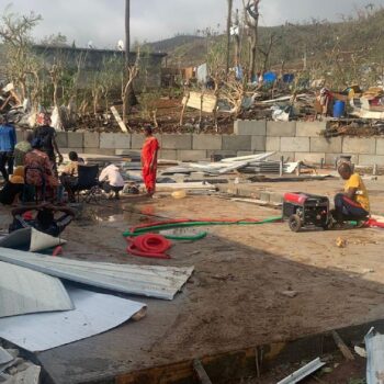 Des habitants assis au milieu de tas de débris de tôles et de bois après la destruction de leurs maisons par le cyclone Chido qui a frappé Mayotte, le 15 décembre 2024