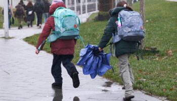 Regen-Wetter: Zwei Kinder mit Schirmen laufen über eine Straße