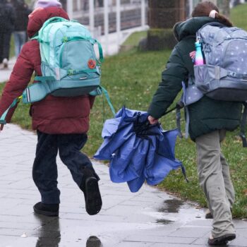 Regen-Wetter: Zwei Kinder mit Schirmen laufen über eine Straße