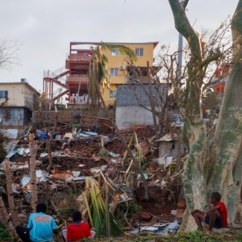 Des habitants assis devant leurs maisons détruites à Mamoudzou après le passage du cyclone Chido à Mayotte, le 17 décembre 2024