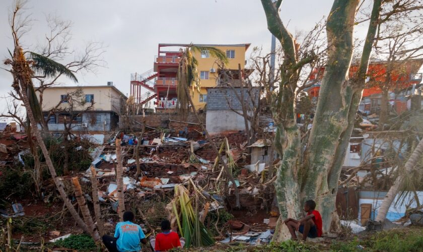 Des habitants assis devant leurs maisons détruites à Mamoudzou après le passage du cyclone Chido à Mayotte, le 17 décembre 2024