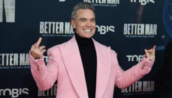 Popstar Robbie Williams im rosa Mantel bei der Premiere seines Films in Köln