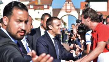 Le président français Emmanuel Macron (C), avec l'officier supérieur de sécurité de l'Élysée Alexandre Benalla (G), serre la main des gens après avoir voté au Touquet, lors du second tour des élections législatives françaises, le 18 juin 2017.