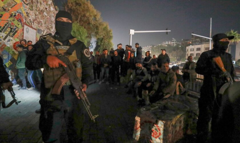 Security forces of the new Syrian government secure the area around group of Alawite protesters in the Mazzeh district in Damascus. Pic: AP