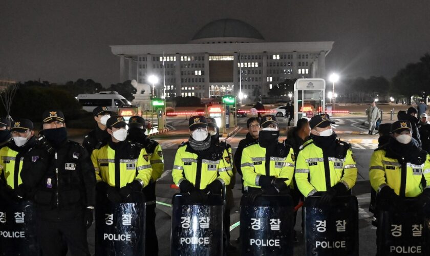 La police monte la garde devant la porte principale de l'Assemblée nationale à Séoul le 3 décembre 2024, après que le président sud-coréen Yoon Suk Yeol a déclaré la loi martiale d'urgence.