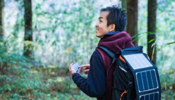 Mann mit Solarzellen, um Smartphone im Wald zu versorgen