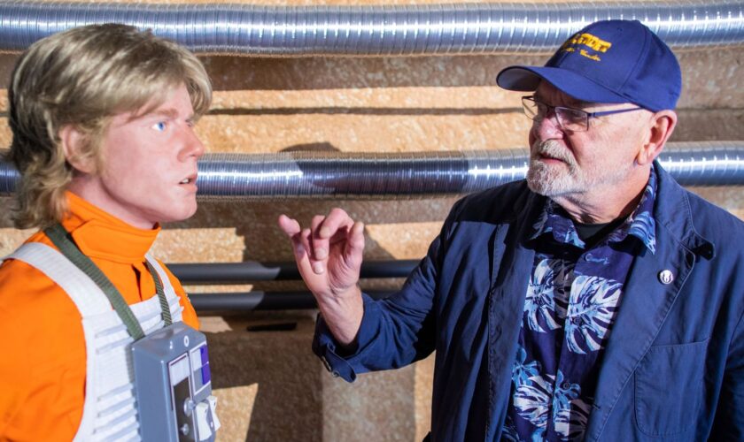 07 September 2019, Mecklenburg-Western Pomerania, Dassow: The American actor Angus MacInnes (r), who played the role of Jon "Dutch" Vander in Star Wars, stands in front of the silicone replica of one of the main characters of the "Star Wars" films, Luke Skywalker, in the collection of the "Outpost One" fan project. The 1,300 square metre exhibition will be officially opened this weekend. With attention to detail and perfectionism, space fans have created a gigantic "Star Wars" world. The visitor