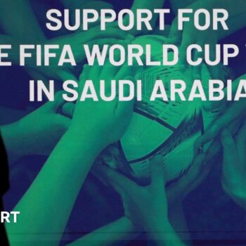 A woman stands in front of a 'support for the Fifa World Cup bid in Saudi Arabia'