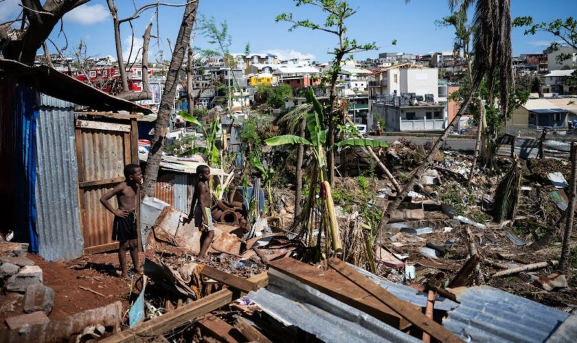 Des enfants au milieu des maisons détruites d'un bidonville endommagé par le cyclone Chido à Mamoudzou, sur le territoire de Mayotte, le 31 décembre 2024